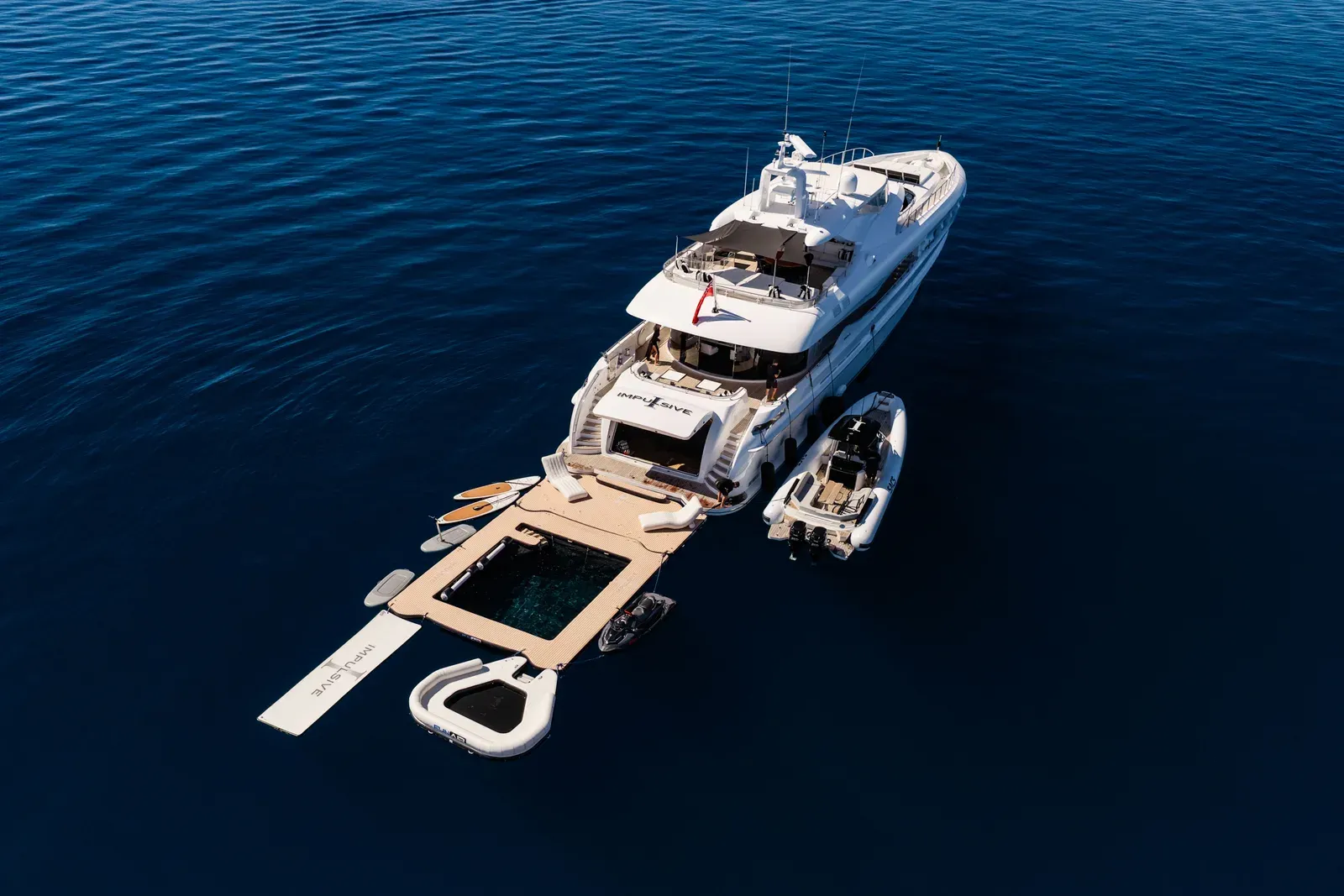 M/Y Impulsive from above on open blue water, tenders and the water platform deployed