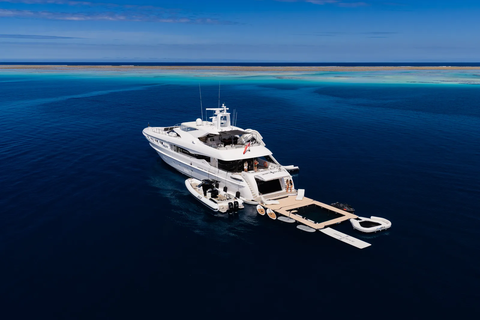 M/Y Impulsive at anchor on the reef edge from the air, tender, sea pool, platform and toys deployed off the stern